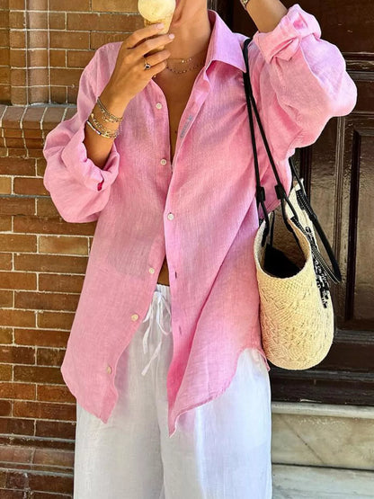 Person wearing a pink shirt and white pants, holding a straw bag and eating an ice cream cone.